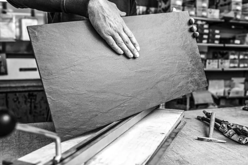 Handwerker hält eine Natursteinplatte, Schwarzweiß-Reportage