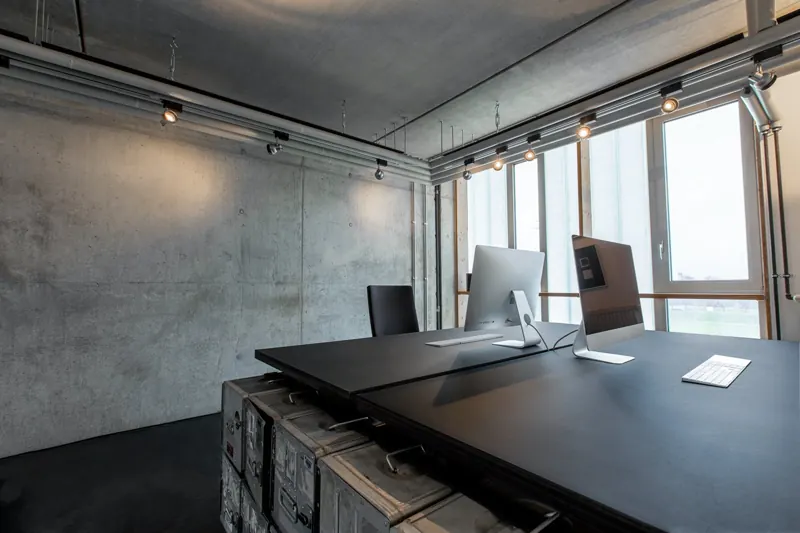 Modernes Büro mit dunklem Schreibtisch und Fensterfront