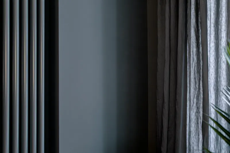 Stimmungsvolles Interieurdetail mit Vorhang und dunkler Wand
