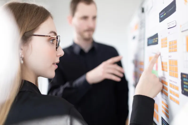 Zwei Mitarbeitende bei einer Besprechung am Whiteboard